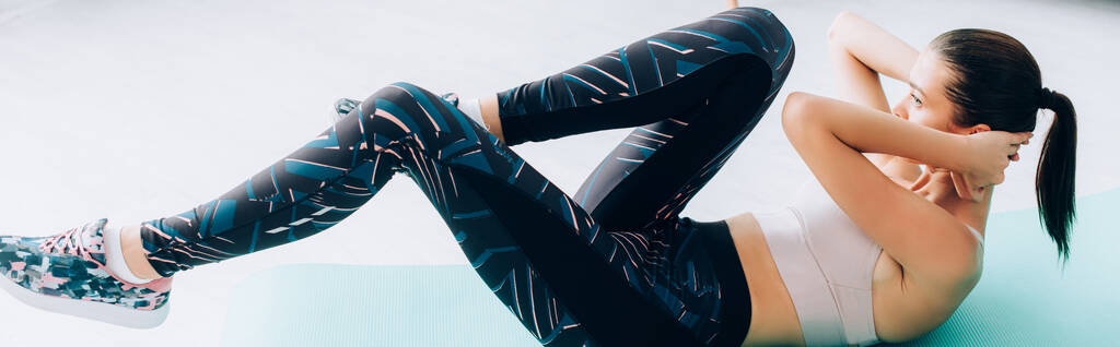 Panoramisch shot van sportvrouw doet buikspieren op fitness mat  - Foto, afbeelding