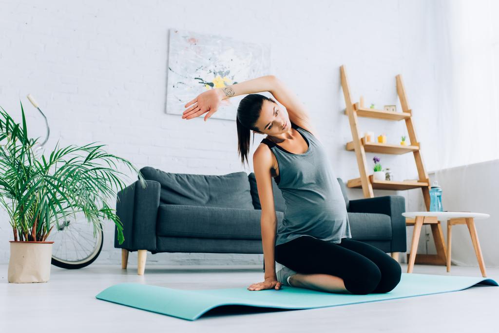 Вибірковий фокус вагітної спортсменки, що розігрівається на фітнес-матусі вдома
  - Фото, зображення