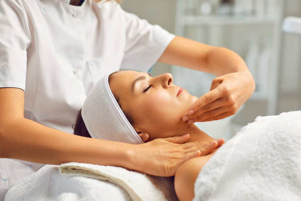 Massage facial ou traitement pour les jeunes femmes visage dans le salon de beauté spa, vue latérale - Photo, image