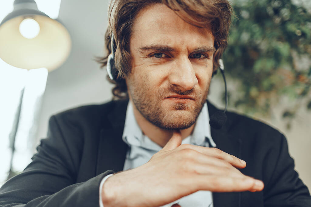 Close-up portret van een boze zakenman met headset met stressvolle online gesprek - Foto, afbeelding