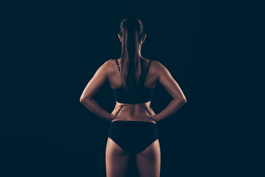リアバック彼女のビューの肖像画の後ろに彼女の素敵な魅力的なコンテンツスポーツ強い筋肉の女性完璧な形状の形状フィットネスモデルボディビルダー手上の黒の背景に孤立した腰 - 写真・画像