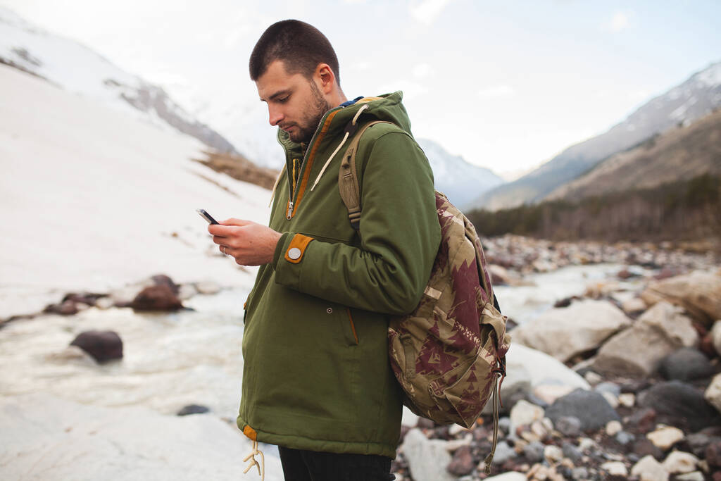 Genç hippi akıllı telefon kullanıyor, vahşi doğa, kış tatili, yürüyüş, seyahat, sırt çantası, kalın kıyafetler. - Fotoğraf, Görsel