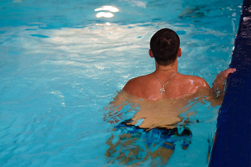 hombre atlético en el agua, vista trasera, agua azul en bossin - Foto, Imagen