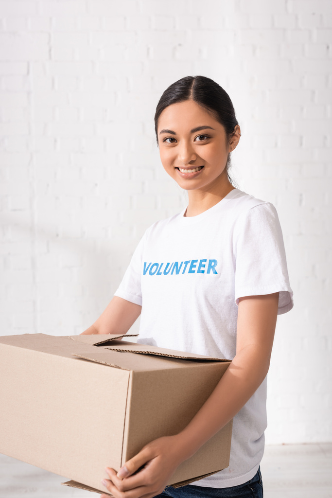 Asian volunteer looking at camera while holding carton box  - Photo, Image