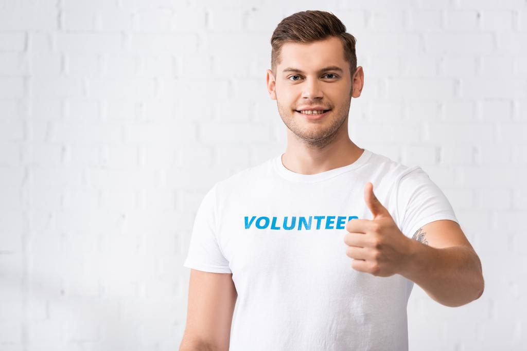 Voluntario en camiseta con letras que muestran el pulgar hacia arriba en el centro de caridad  - Foto, Imagen