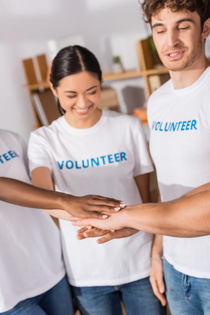Selektiver Fokus multiethnischer Freiwilliger beim Händchenhalten in Wohltätigkeitszentrum  - Foto, Bild