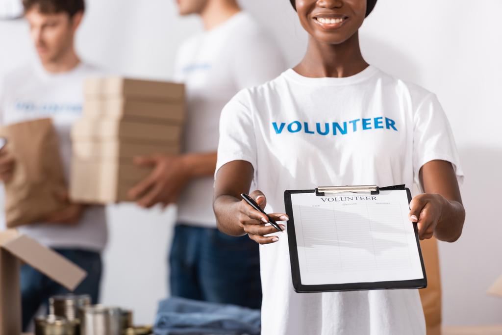 クリップボードとペンを慈善センターで保持するアフリカ系アメリカ人ボランティアの選択的焦点  - 写真・画像