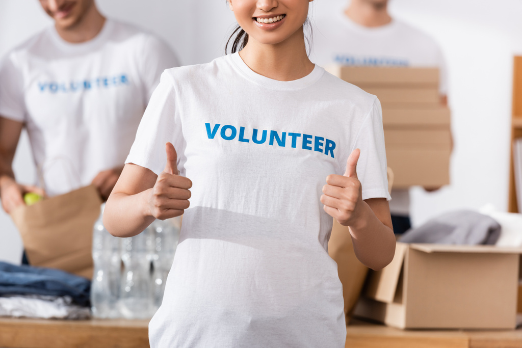 Vista recortada del voluntario mostrando como gesto cerca de donaciones en el centro de caridad  - Foto, Imagen