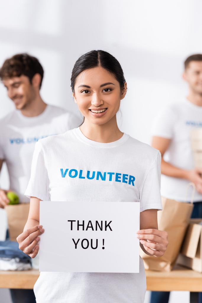 Selectieve focus van Aziatische vrijwilliger holding card met dank u belettering in liefdadigheidscentrum  - Foto, afbeelding