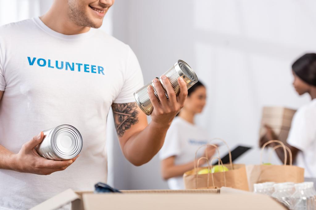 Вибірковий фокус волонтера, який тримає олов'яні банки біля пакету в благодійному центрі
  - Фото, зображення