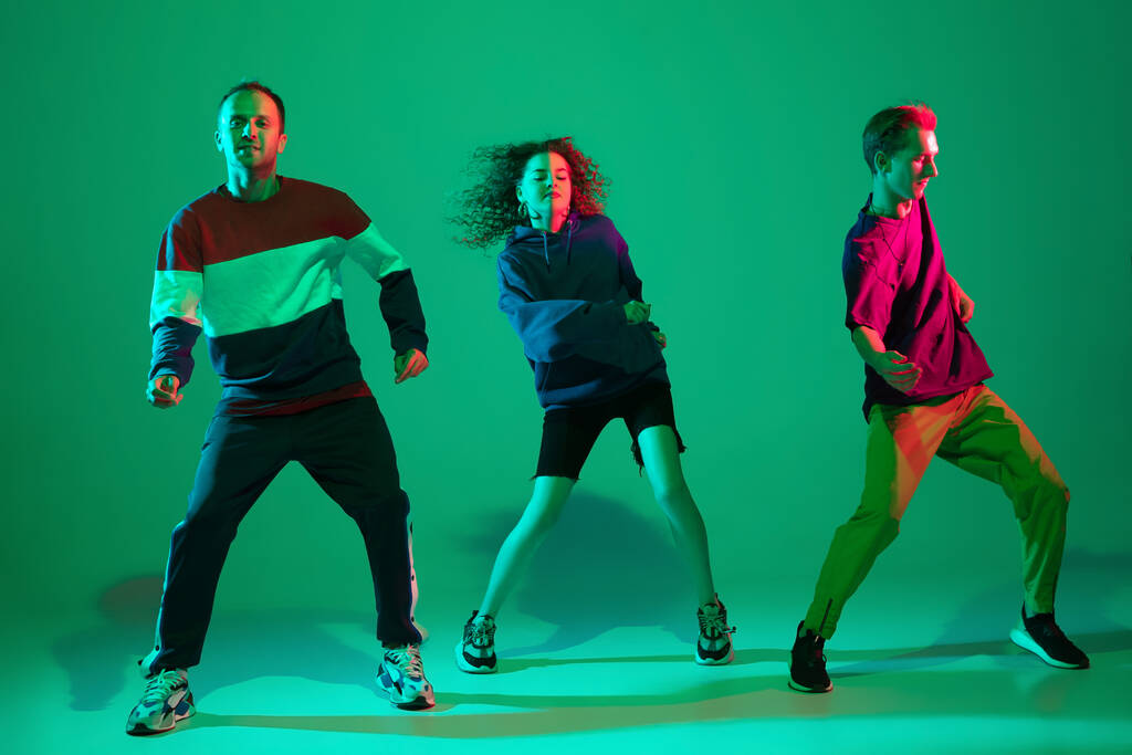 Uomini e donne alla moda che ballano hip-hop in abiti luminosi su sfondo sfumato nella sala da ballo in luce al neon - Foto, immagini
