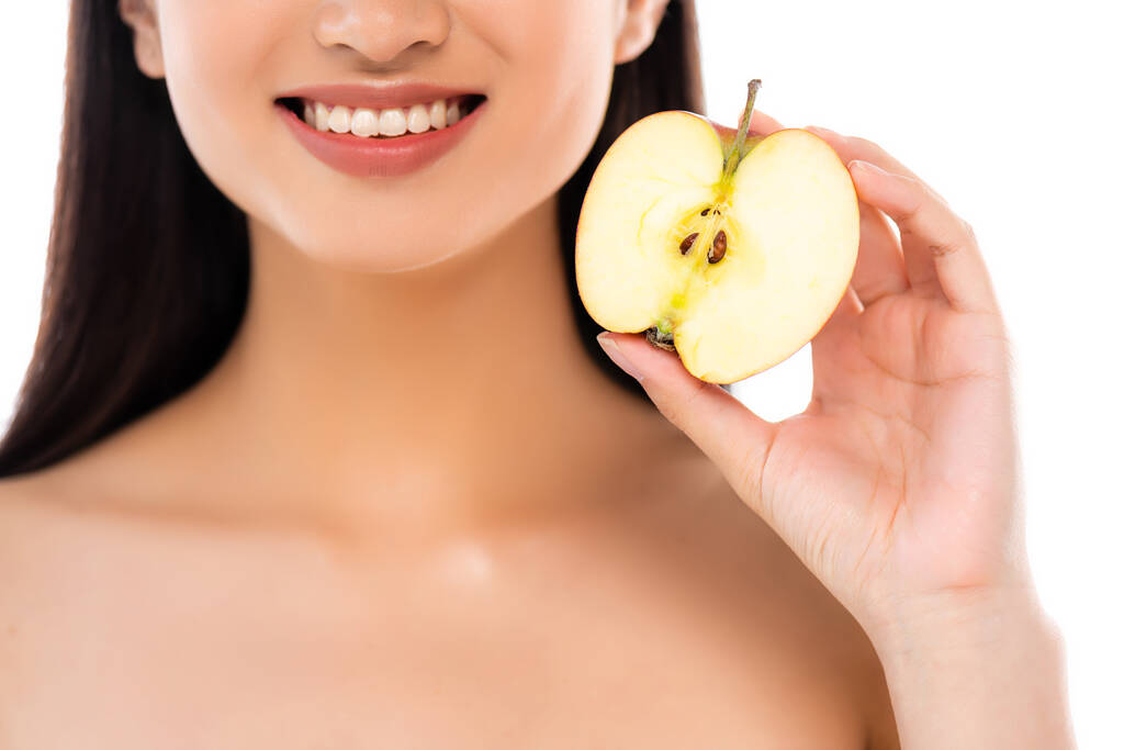 Частичный снимок возбужденной молодой женщины, держащей половину яблока изолированной на белом - Фото, изображение