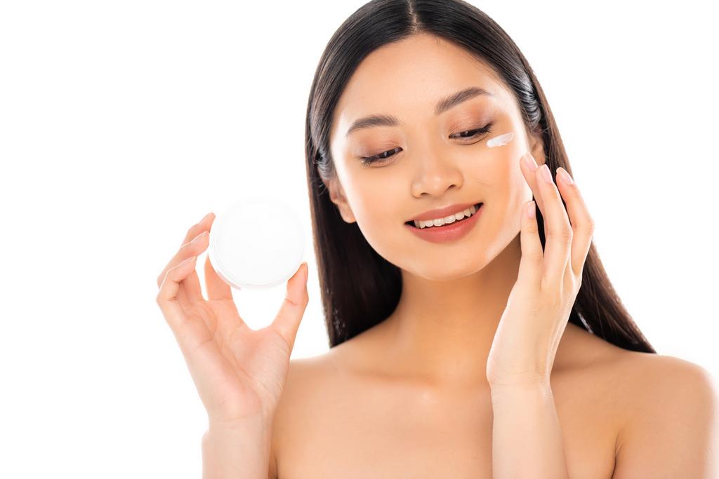 mujer asiática desnuda aplicando crema cosmética en la cara aislada en blanco - Foto, Imagen