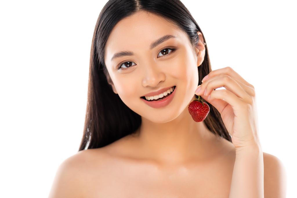 nackte asiatische Frau hält saftige Erdbeere, während sie in die Kamera schaut, isoliert auf weiß - Foto, Bild