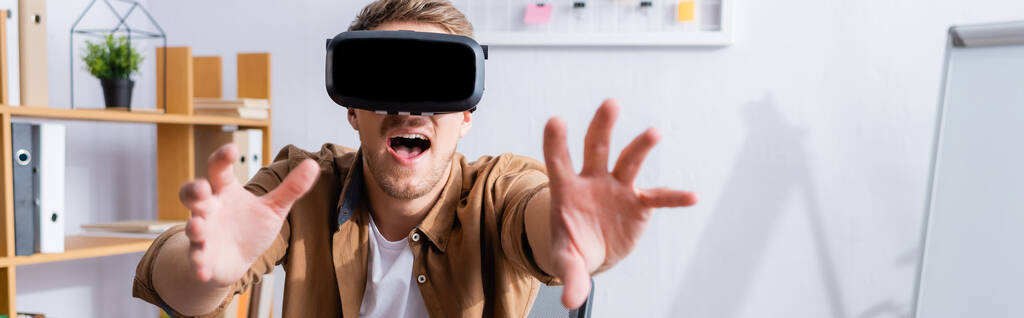 imagen horizontal del empresario excitado haciendo gestos mientras usa auriculares vr en la oficina - Foto, imagen