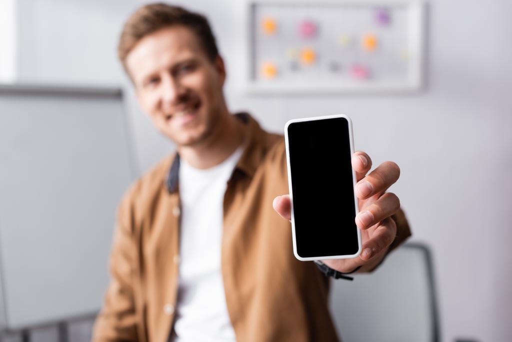 Enfoque selectivo del hombre de negocios mostrando teléfono inteligente con pantalla en blanco en la oficina  - Foto, Imagen