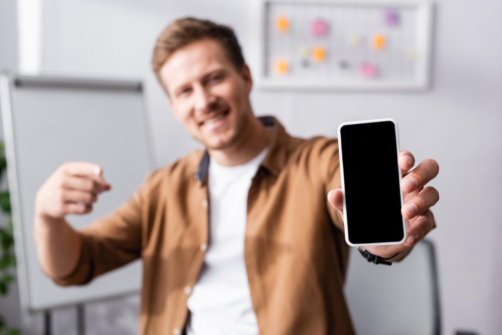 Selektivní zaměření podnikatele ukazující prstem na smartphone s prázdnou obrazovkou v kanceláři  - Fotografie, Obrázek