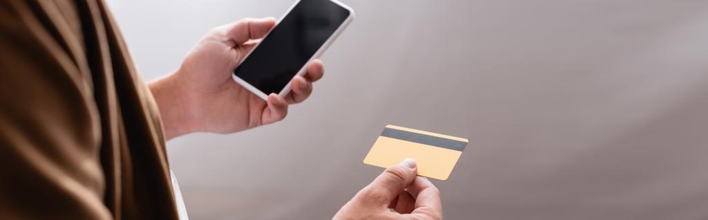 Vue panoramique d'un homme d'affaires tenant un smartphone et une carte de crédit  - Photo, image