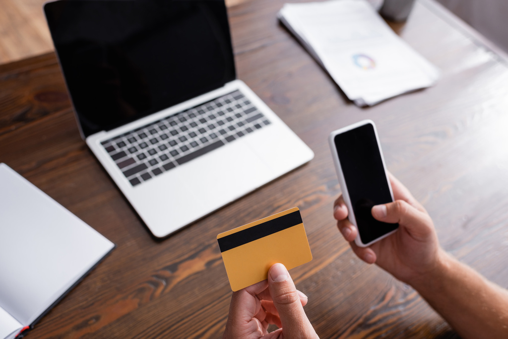 Gesneden weergave van de zakenman met smartphone met blanco scherm en creditcard in het kantoor  - Foto, afbeelding