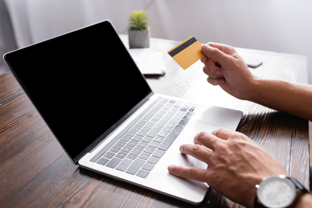 Widok biznesmena korzystającego z laptopa i karty kredytowej przy stole w biurze  - Zdjęcie, obraz