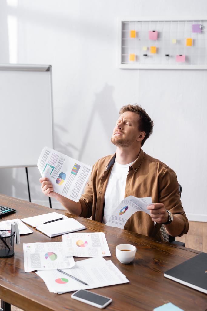 Вибірковий фокус стресового бізнесмена, який тримає папери за столом
  - Фото, зображення