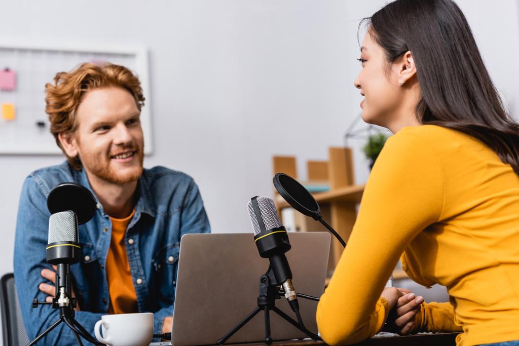 selective focus of brunette asian woman talking to young redhead radio host during interview - Photo, Image