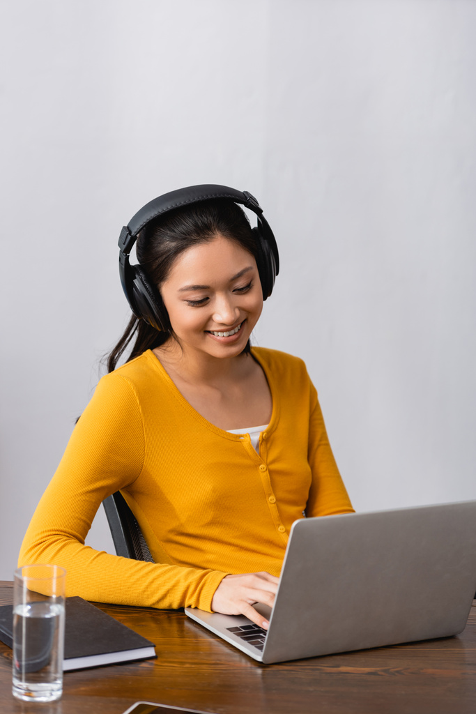 barna ázsiai szabadúszó vezeték nélküli fejhallgató gépelés laptop otthon - Fotó, kép