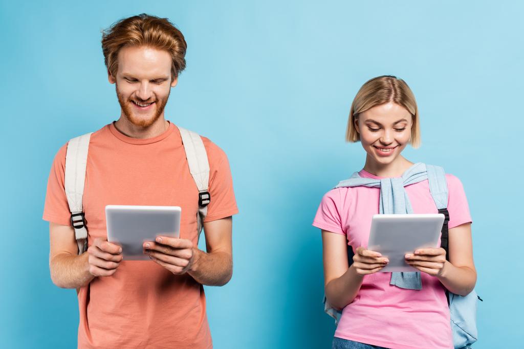 Junge Studenten betrachten digitale Tablets auf blauem Grund - Foto, Bild