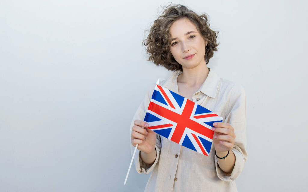 Portret studenta trzymającego flagę Wielkiej Brytanii. Młoda kobieta trzymać flagę UK. - Zdjęcie, obraz