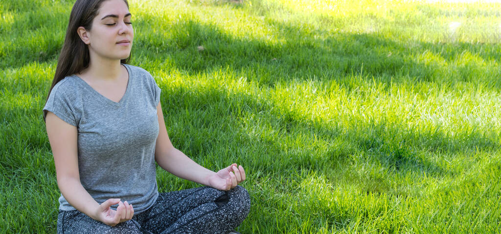 Egy közeli kép egy fiatal kaukázusi nőről, amint meditál egy parkban. - Fotó, kép