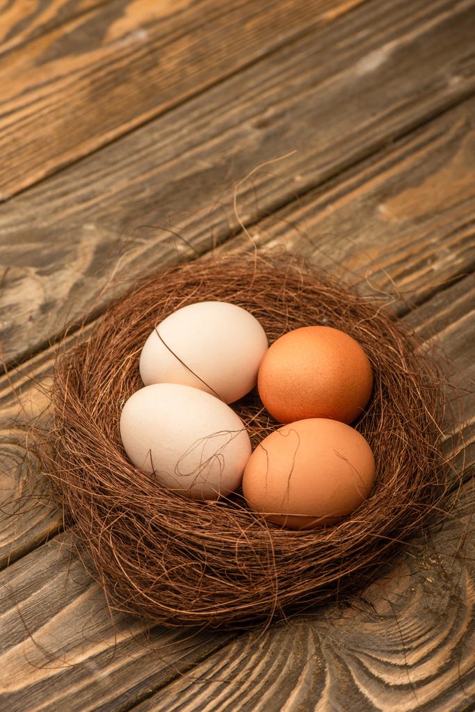 φρέσκα αυγά κοτόπουλου στη φωλιά σε ξύλινη επιφάνεια - Φωτογραφία, εικόνα