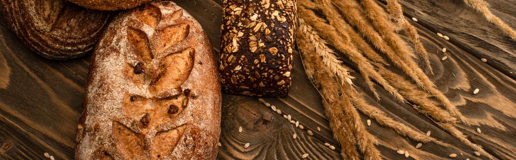 vers gebakken brood broden met spikeletten op houten oppervlak, panoramisch schot - Foto, afbeelding