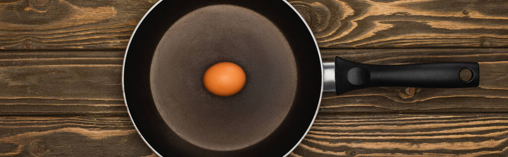 top view of raw chicken egg in frying pan on wooden surface, panoramic shot - Photo, Image