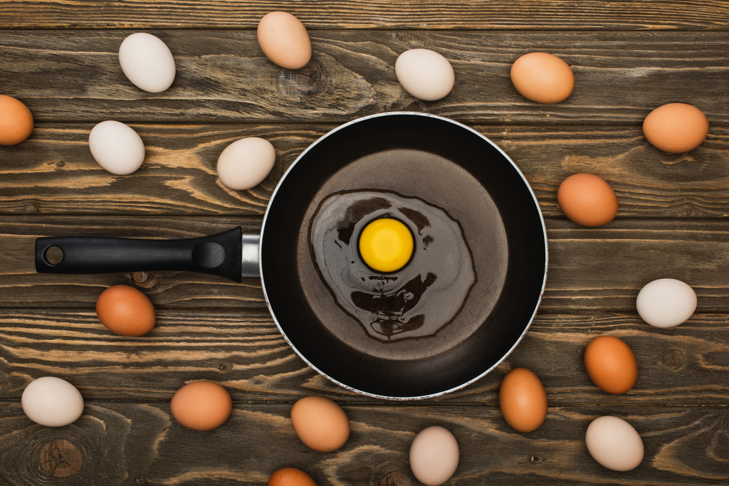 felülnézet friss csirke tojás és serpenyő fából készült felületen - Fotó, kép