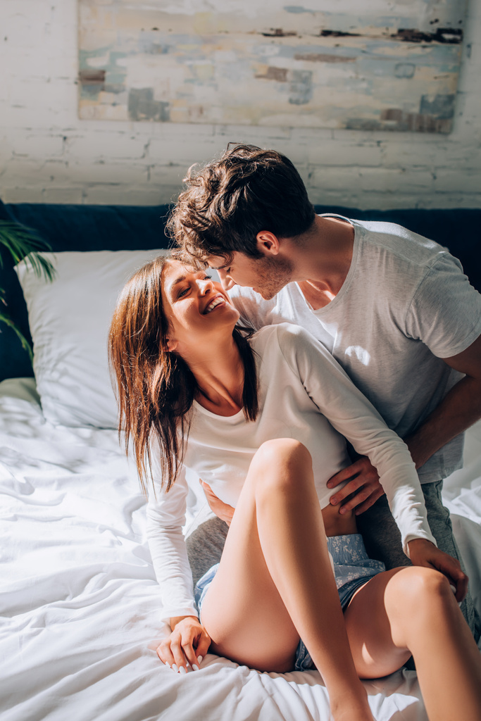 Homem alegre abraçando e olhando para a namorada na cama - Foto, Imagem