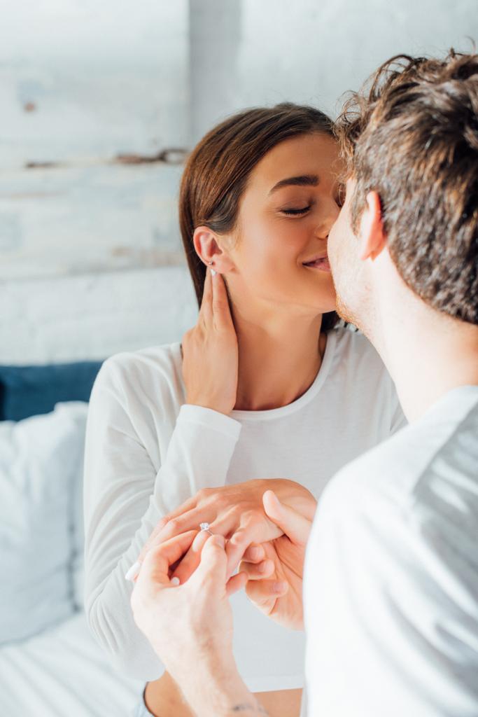 Selectieve focus van jong koppel kussen tijdens het huwelijk voor te stellen in de slaapkamer  - Foto, afbeelding
