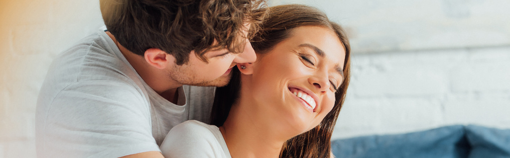 Cosecha horizontal del hombre mirando a su novia con los ojos cerrados en casa  - Foto, Imagen