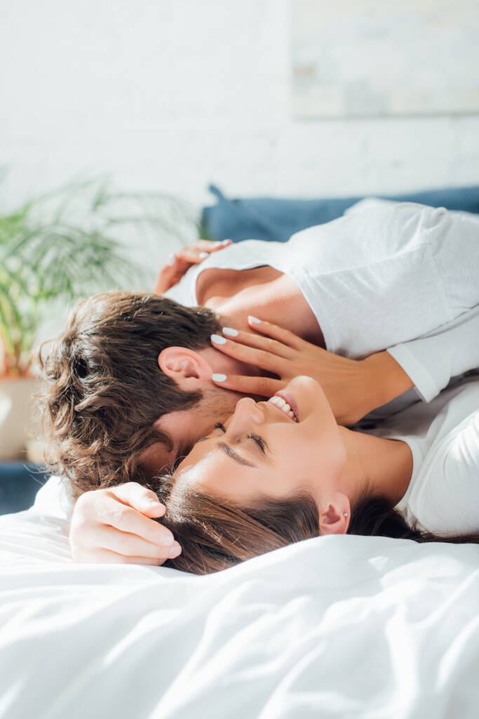 Homme embrasser petite amie tout allongé sur le lit le matin  - Photo, image