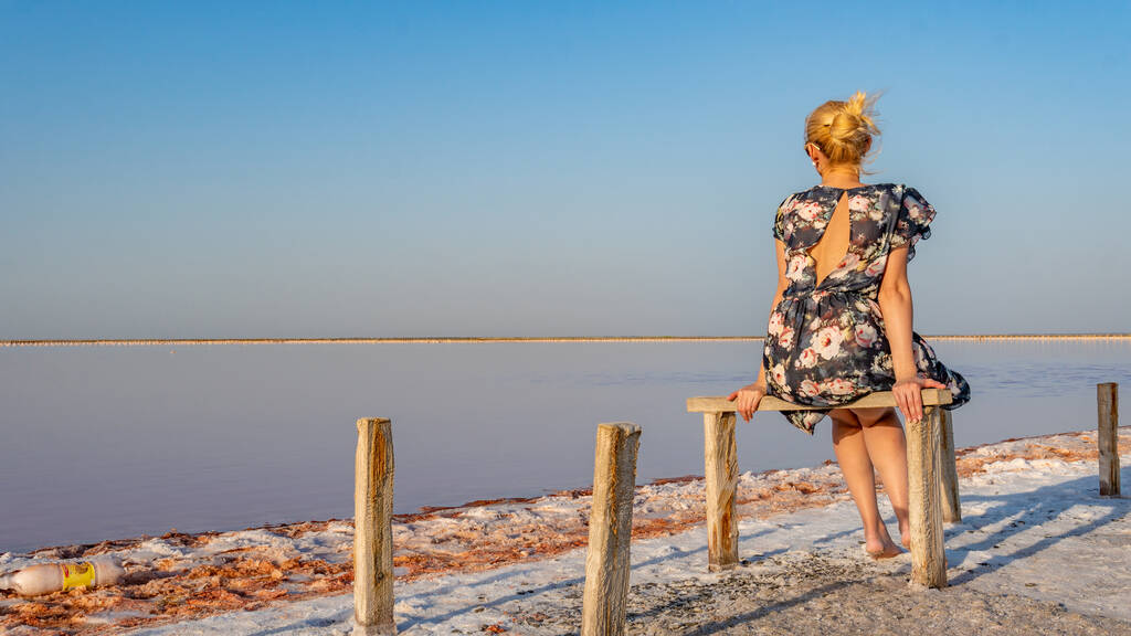 dame in een mooie jurk volwassene met een mooie glimlach op de achtergrond van een wit meer van zout met blauwe wolken op een zomerdag - Foto, afbeelding