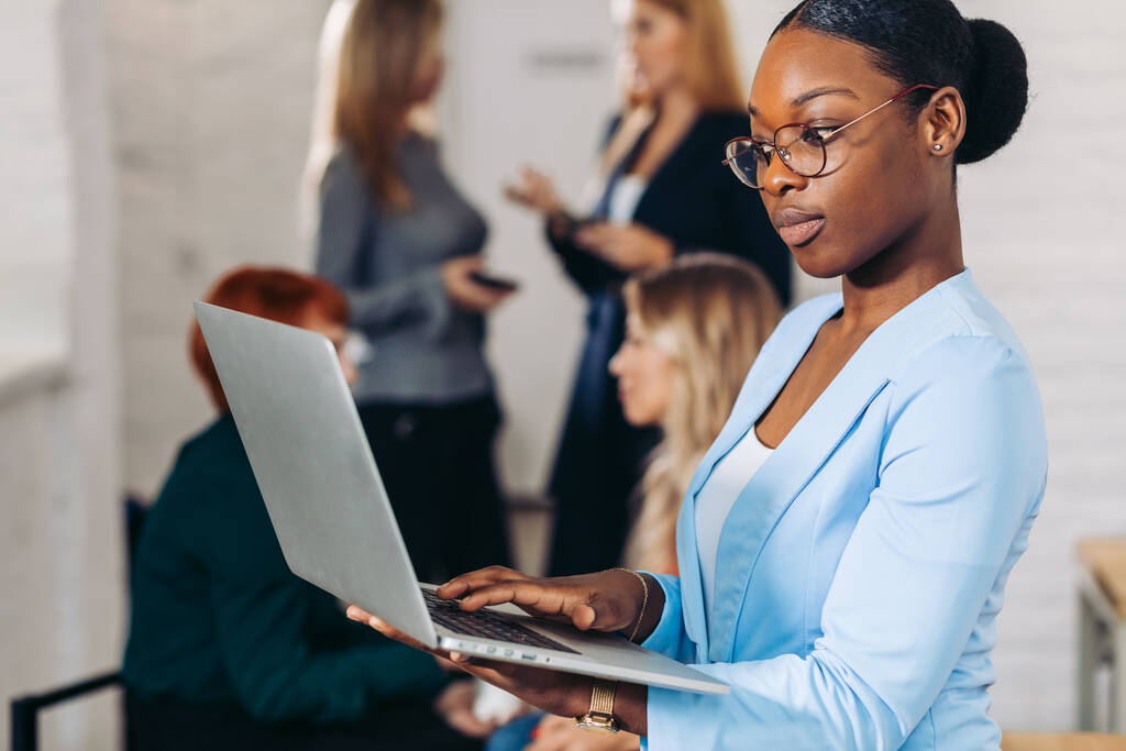 üzlet fekete nő beállítása laptopját, áll a kollégák mögött - Fotó, kép