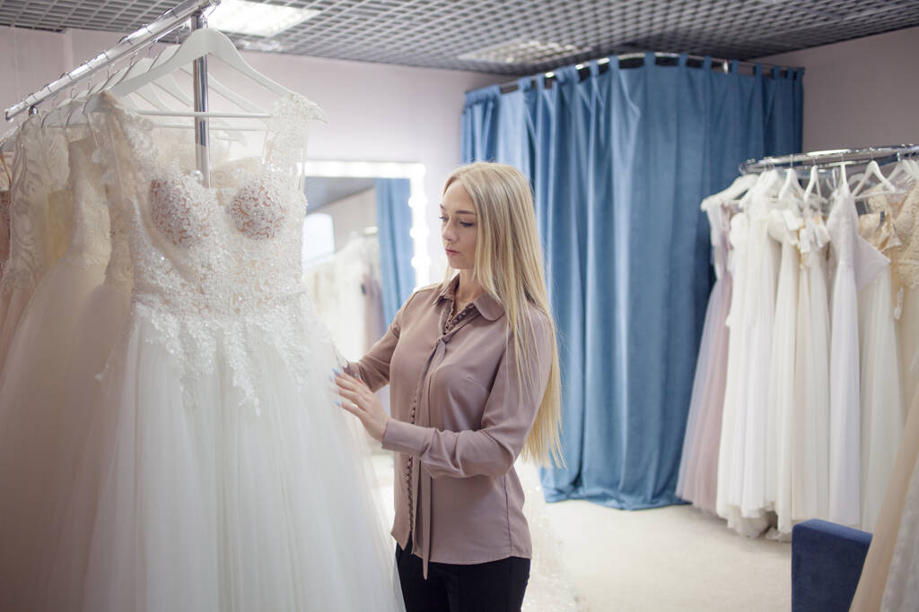 mladá blondýna žena si vybere svatební šaty ve svatebním salonu. - Fotografie, Obrázek