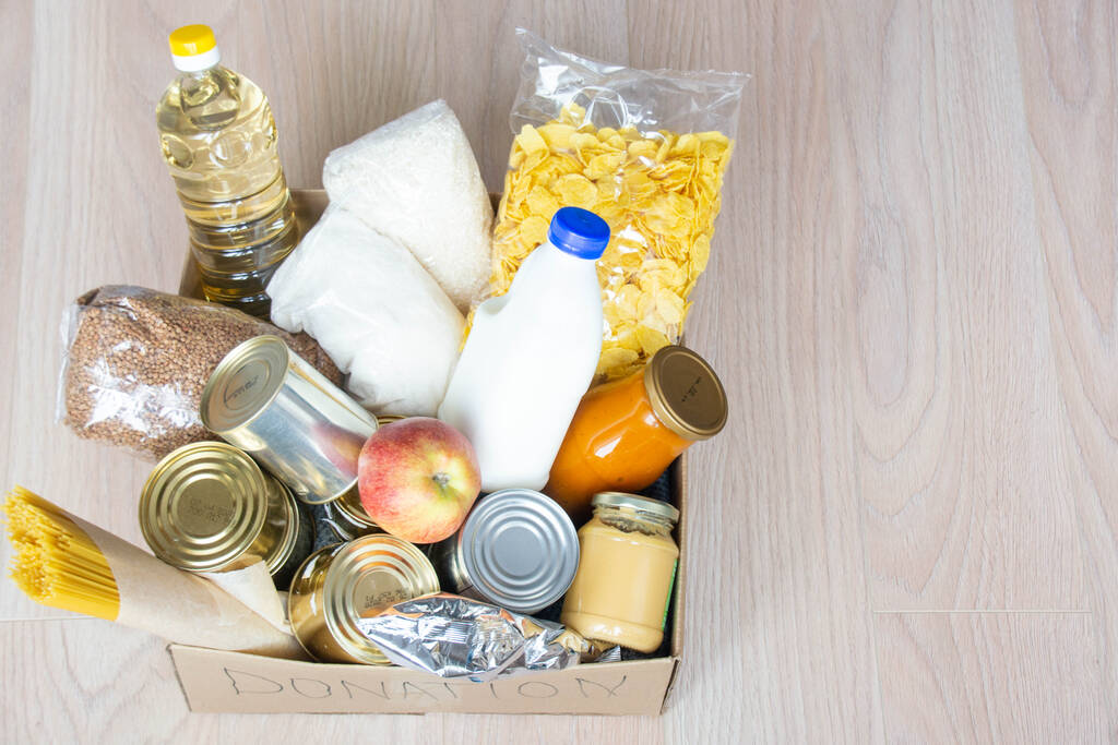 Různé konzervované potraviny, těstoviny a cereálie v papírové krabici. Darování potravin nebo koncepce dodání potravin. - Fotografie, Obrázek