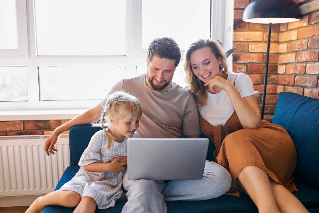 valkoihoinen perhe istuu kannettavan tietokoneen avulla kotona sohvalla - Valokuva, kuva