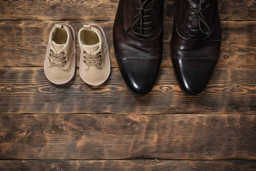 Zapatos del bebé y del padre en el piso de madera plano ponen fondo con espacio de copia. - Foto, Imagen