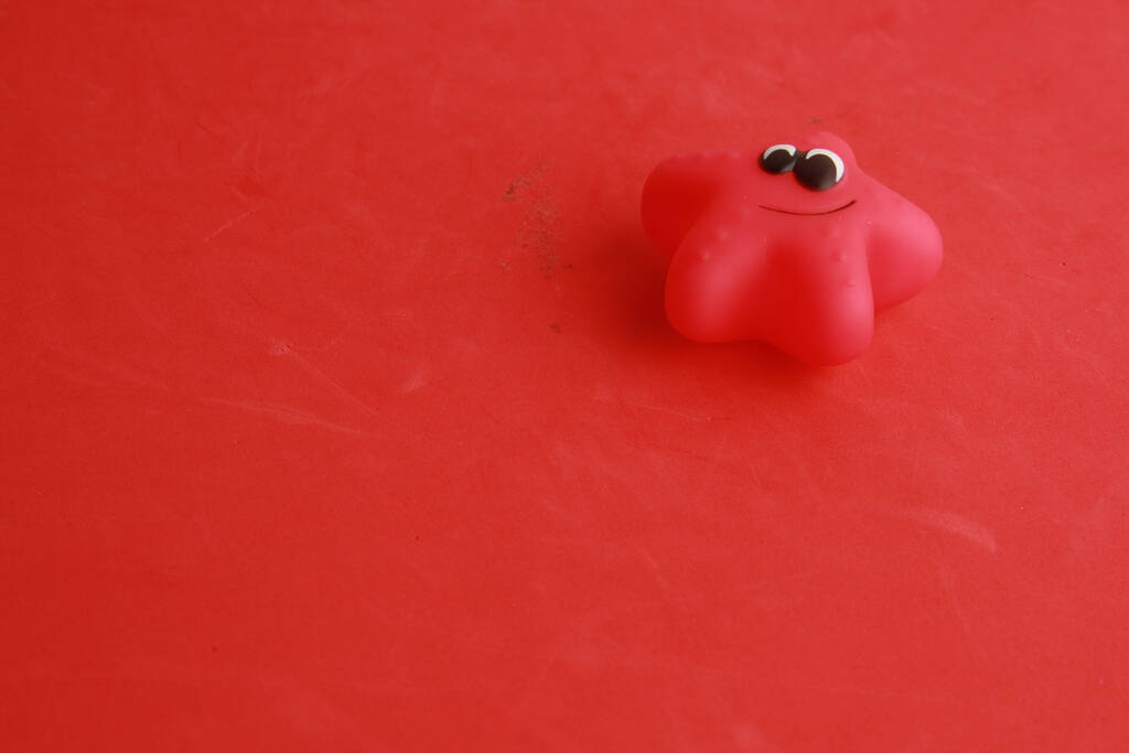 Un giocattolo di stelle marine di gomma su una superficie rossa - Foto, immagini