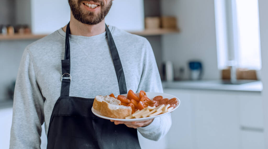 Тарелка сэндвичей в руках привлекательного мужчины - Фото, изображение