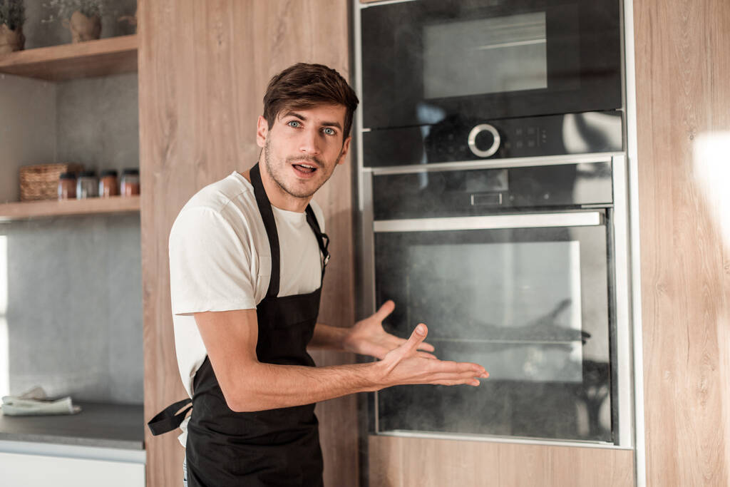 emotional young man standing near broken oven - Photo, Image