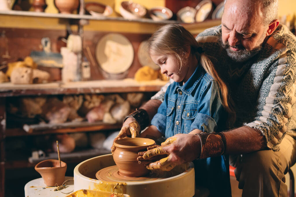 Керамическая мастерская. Дедушка преподает керамику внучке. Моделирование глины - Фото, изображение