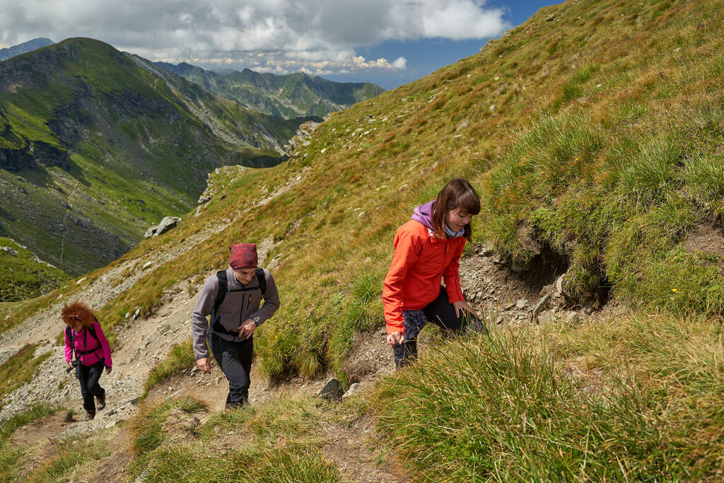 A hegyekbe vezető meredek ösvényen mászó túrázók családja - Fotó, kép