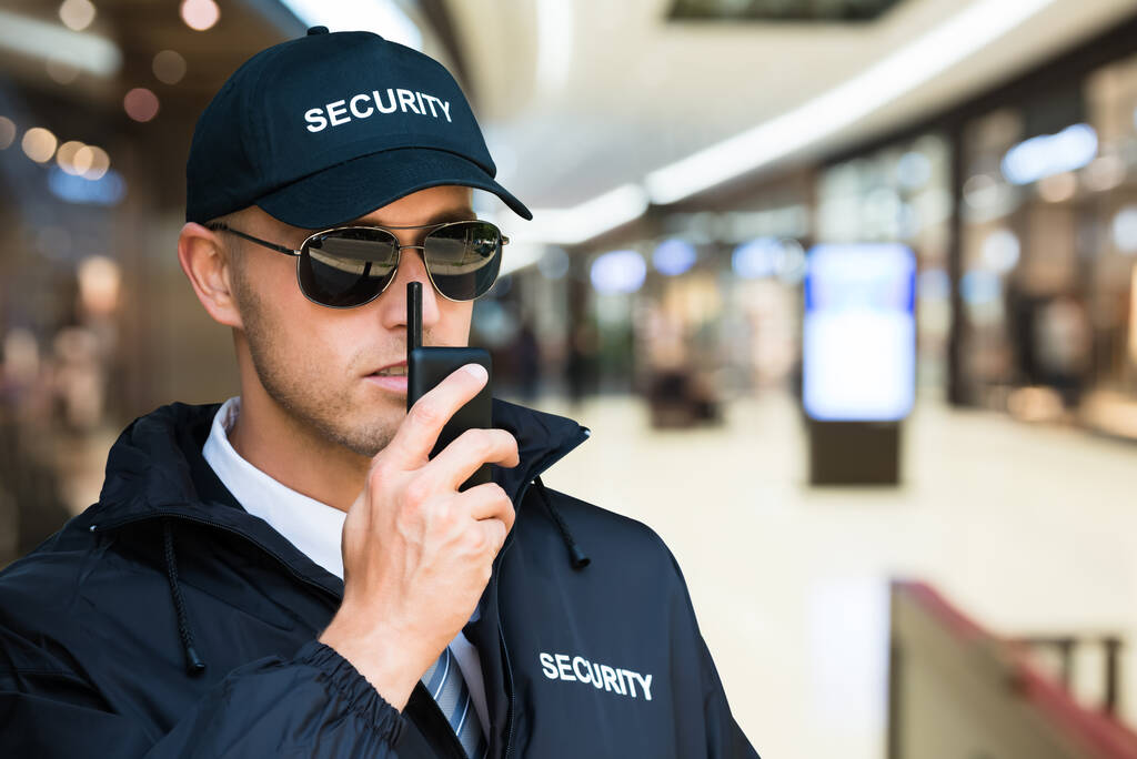 Guarda de segurança usando Walkie Talkie no shopping
 - Foto, Imagem